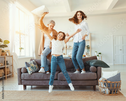 Slika na platnu family three generations  grandmother, mother and child dancing, jumping and laugh at home