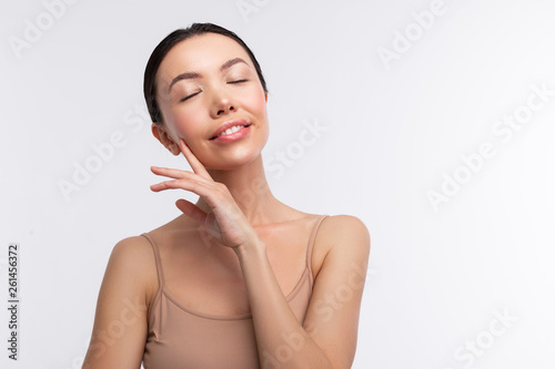 Obraz na plátne Dark-haired woman wearing beige camisole closing her eyes