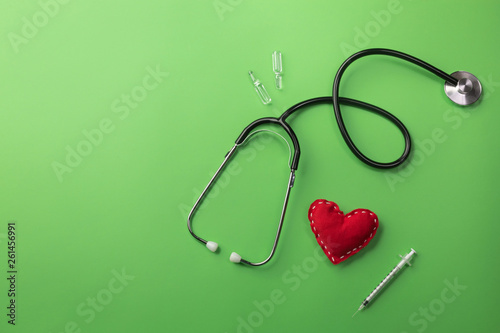 Stethoscope in doctors desk with heart, syringe and ampoules
