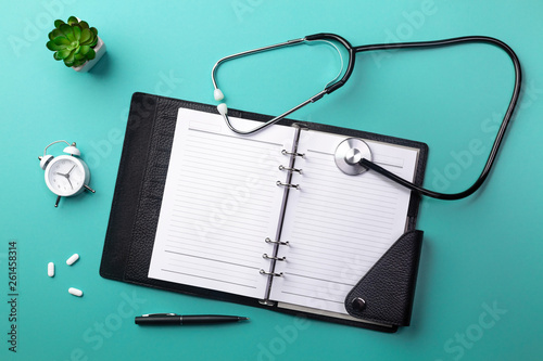 Stethoscope in doctors desk with notebook, keyboard, mouse, glasses, syringe, ampoules, inhaler and pills