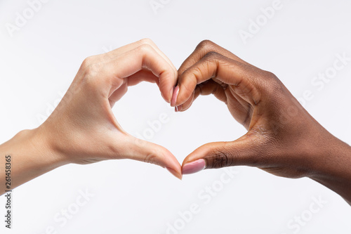 Cuadro en lienzo Women with white and black skin showing heart with their hands