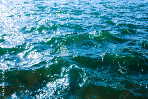 sea ripples; blue clear deep water with small waves close up; sun glare on the water