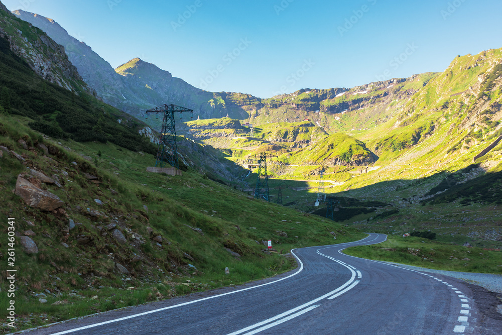 Fototapeta premium transfagarasan road at sunrise. popular travel destination of romania. beautiful summer landscape in mountains. road winding uphill through gorge with steep rocky cliffs