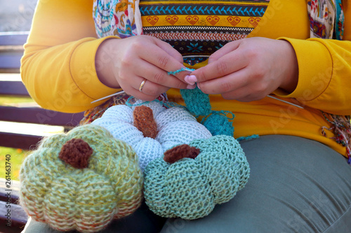 Hands of woman knits a decorative pumpkin with needles. Close up of hands knitting. Process of knitting.
