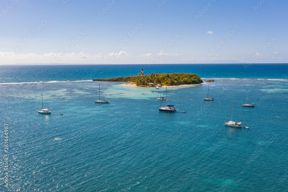 Scenic aerial view of Le Gosier island near La Datcha beach in Guadeloupe. Beautiful summer sunny look of small paradise tropical island in Caribbean sea. Several boats and yachts in blue sea.