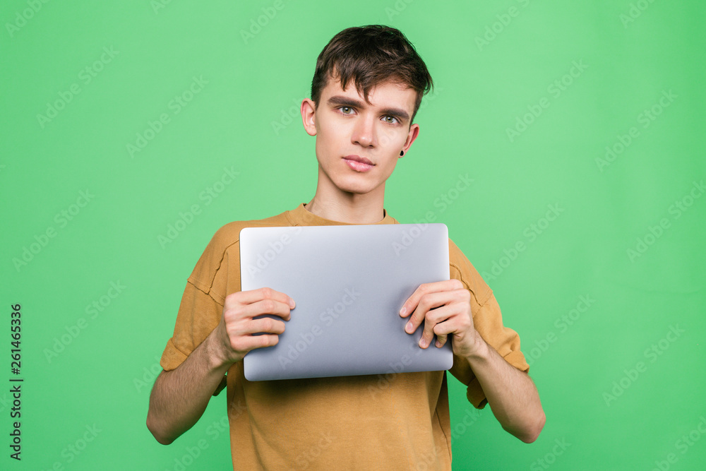Young guy holding a laptop standing on a green background