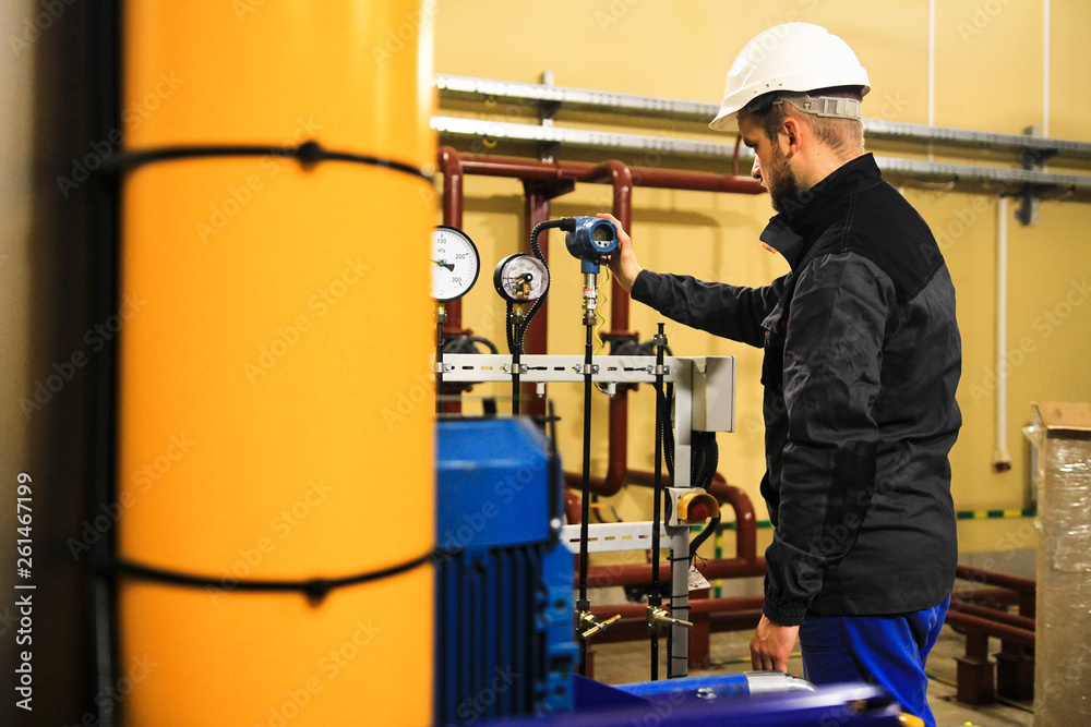 Engineering staff adjusts the parameters of digital pressure sensor at industrial plant
