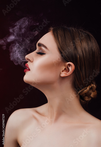 naked woman with red lips blowing smoke, isolated on black 