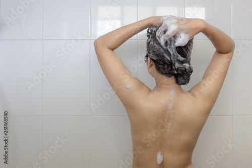 Young asian woman taking a shower and washing hair in white bathroom