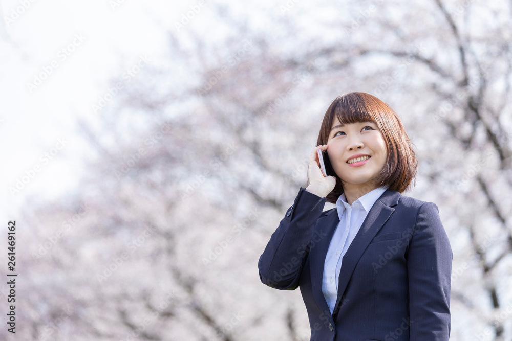 桜とスーツの女性