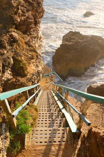 Iron staircase over rocks to the viewpoint of the lighthouse in the city of Nazare in Portugal