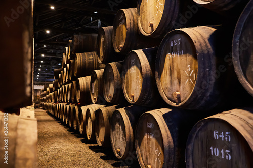 Old aged traditional wooden barrels with wine in a vault lined up in cool and da Fototapet