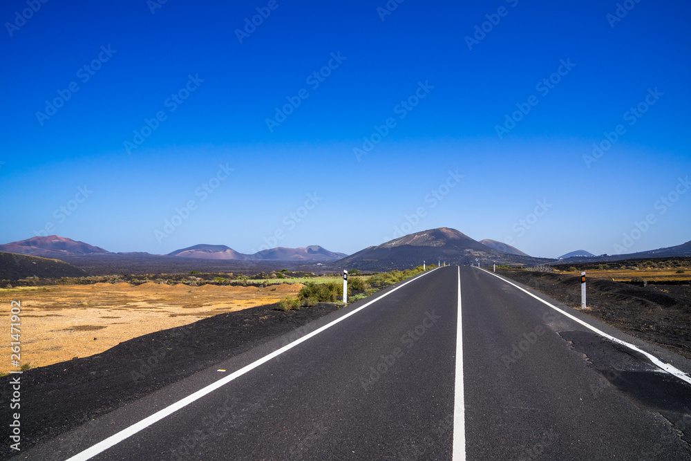 Spain, Lanzarote, Black asphalt road alongside pretty volcanic nature landscapes and volcanoes Spain, Lanzarote, Black asphalt road alongside pretty volcanic nature landscapes and volcanoes