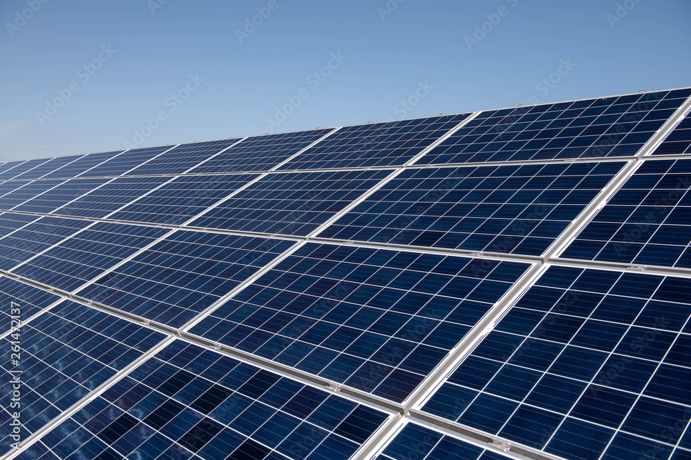 Close up clean solar panels on blue clear sky background producing friendly environment energy. Alternative electricity source Close up clean solar panels on blue clear sky background producing friendly environment energy. Alternative electricity source