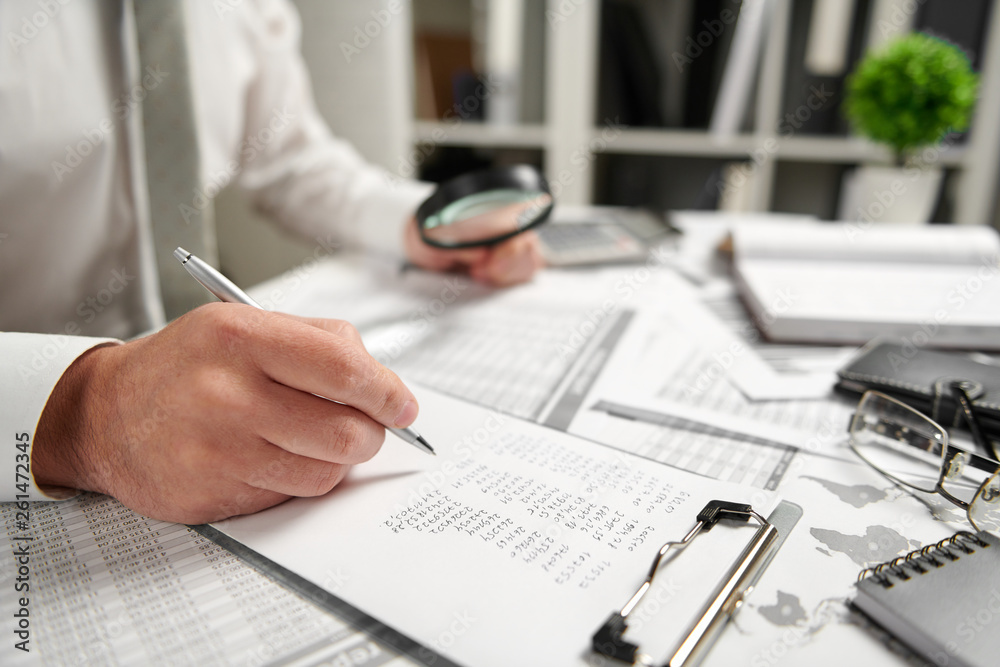 Fototapeta premium Businessman working at office and calculating finance, reads and writes reports. Business financial accounting concept.