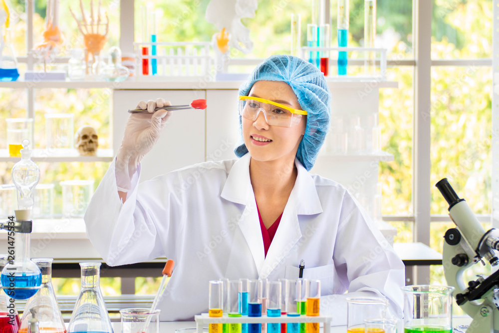 Scientists look at a cotton ball that is attached to a red chemical