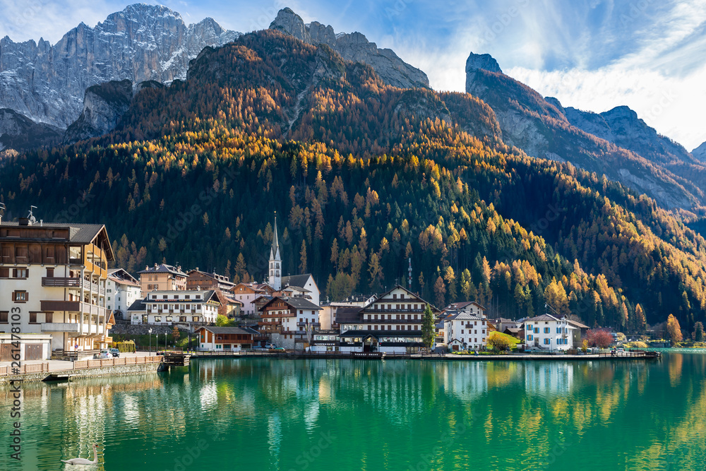 Alpine town surrounded by mountains and lakes, white swan swimming on a lake 
