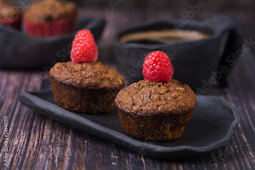 homemade muffin with raspberry and black clay dish on a rustik style wood table
