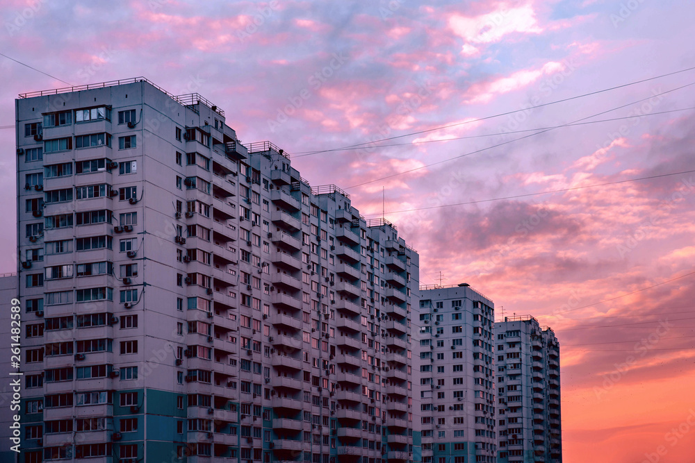 Sunset evening high rise residential apartment building with a lot of windows. Beautiful pink purple sky. Moody cityscape Sunset evening high rise residential apartment building with a lot of windows. Beautiful pink purple sky. Moody cityscape