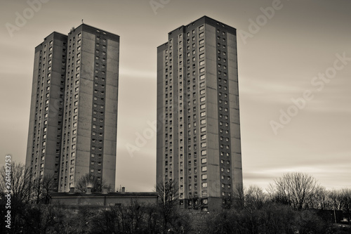 A black and white shot of two towers of flats with a grey sky behind