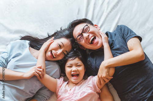 Happy Asian family laying on bed smile, top view photo