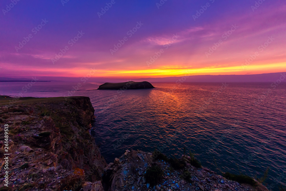 ship sails on a background of purple sunset sky on the waves of Lake Baikal from Olkhon