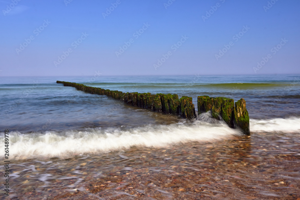 sandy beach and wooden breakwaters on the Baltic coast in  Poland.