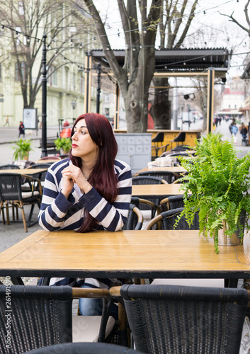 Young lady with long hair sitting alone in cafe