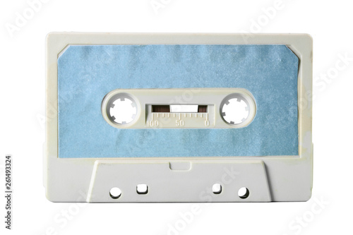An old vintage cassette tape, obsolete music tech from the 1980s. Dirty ice grey plastic body, cyan blue worn label. Isolated item.