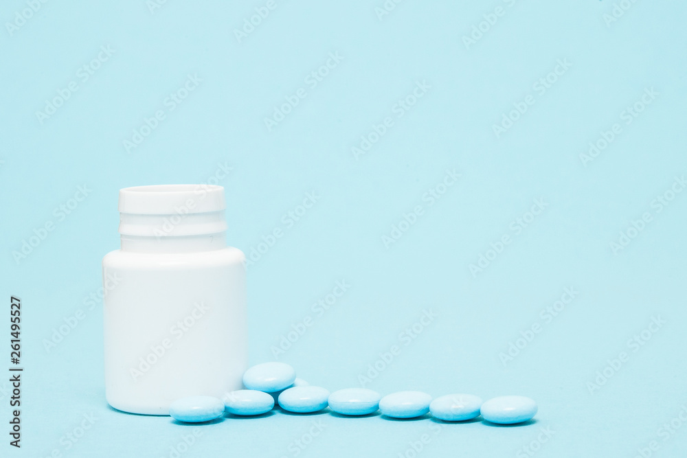 Blue pills and pill bottle on blue background Blue pills and pill bottle on blue background