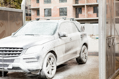 Car wash with foam in car wash station. Carwash. Washing machine at the station. Car washing concept. Car in foam © volody10