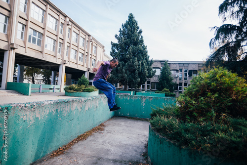 Strongman while training parkour jumping over the concrete wall at an urban area. © qunica.com