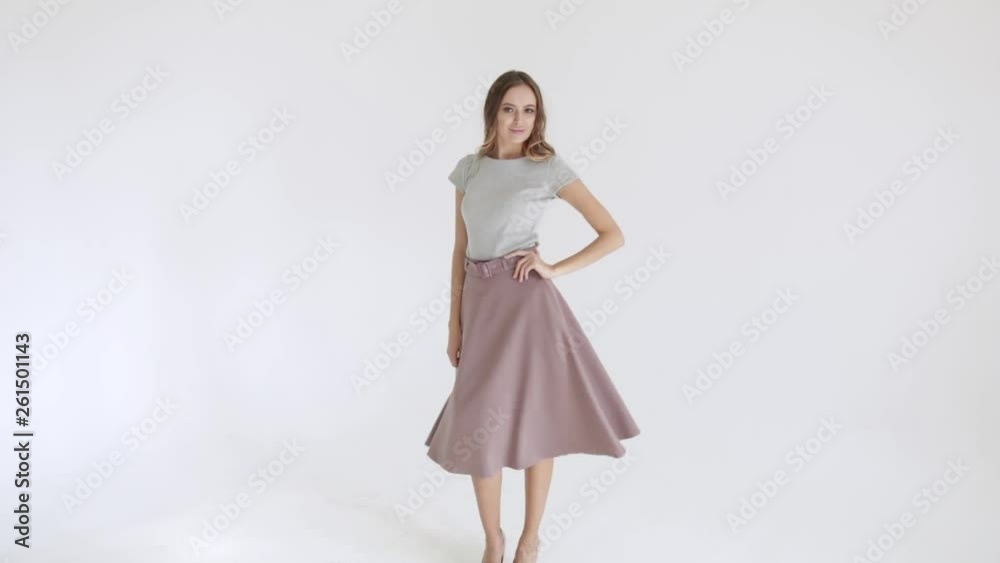 Attractive girl dancing and spinning with grey dress. Cute brunette smiling and having fun on white background Attractive girl dancing and spinning with grey dress. Cute brunette smiling and having fun on white background