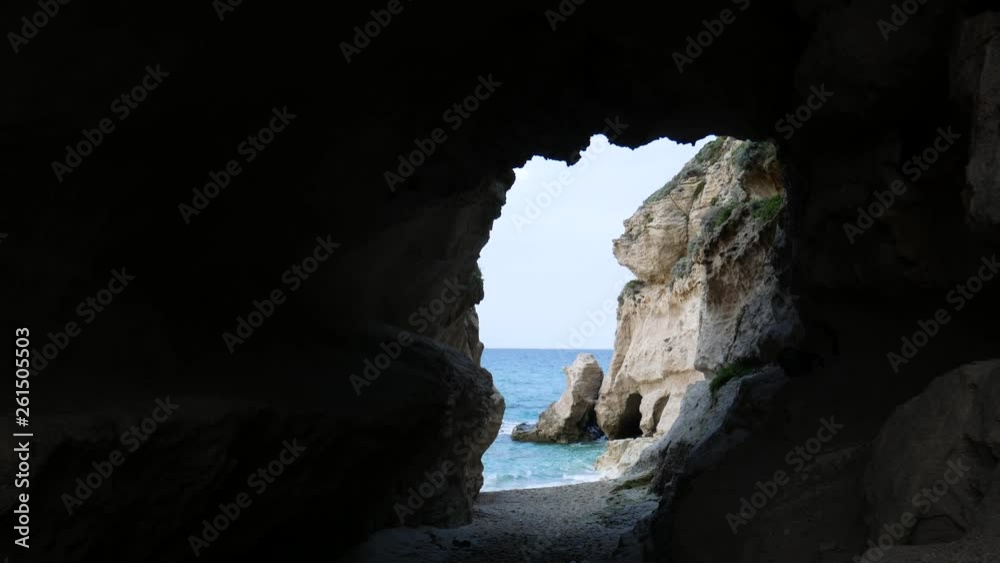 waves stand out on the rocky cliff on the sea at sunset. Calabrian emerald sea seen through a marine grotto (cave). Tropea, Calabria, Italy