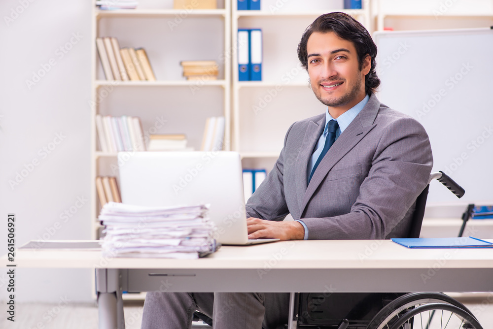 Young handsome employee in wheelchair at the office Young handsome employee in wheelchair at the office