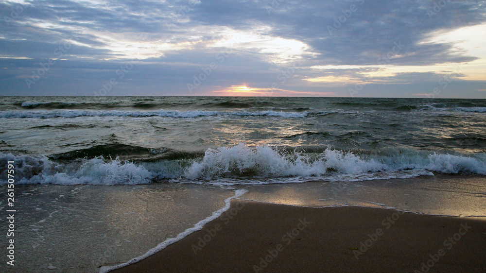 Summer evening sunny sunset in the sea on the shore. Sandy coast on the ocean.