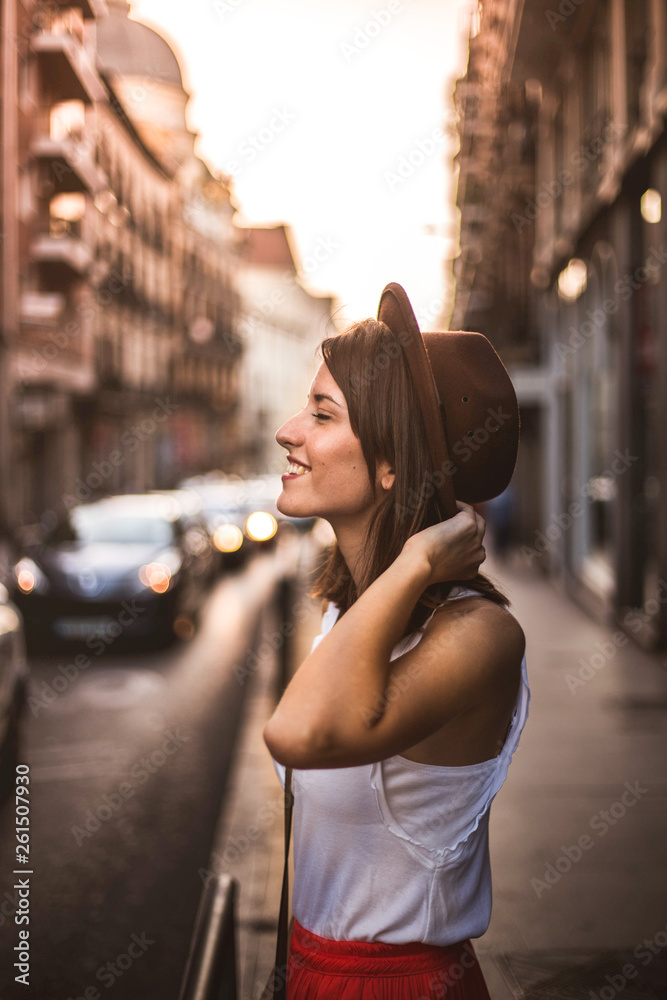 Young woman with hat enjoying tourism on a street in Madrid, Spain