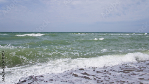 Summer day sea turquoise waves hit the shore. Sandy coast of the ocean.