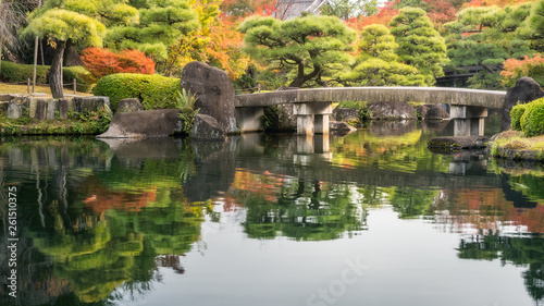 Pictorial scene at Koko-en Gardens in Himeji, Japan with the classical bridge over the pond and spectacular autumn foliage reflected in the water.