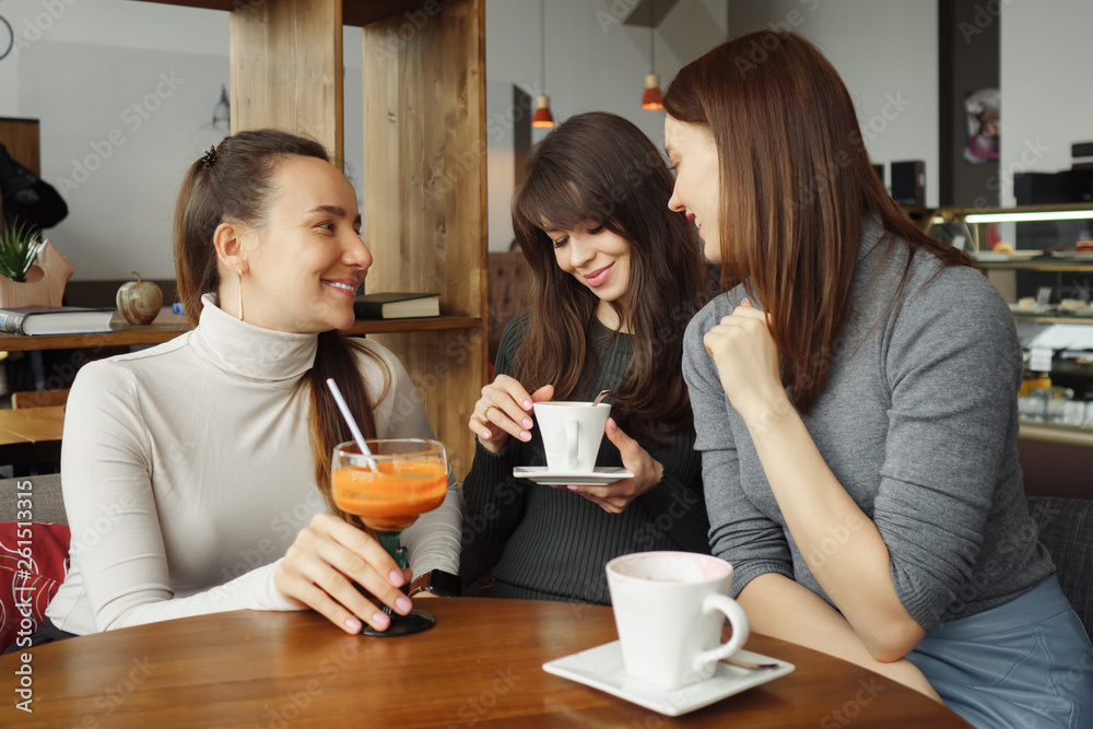 Three women girlfriends in a cafe are talking and drinking their beverages. Three women girlfriends in a cafe are talking and drinking their beverages.