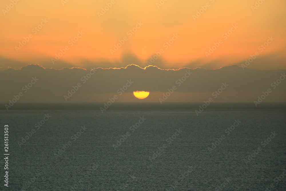 Naklejka premium Golden sunset light breaks through the sky with clouds over the ocean