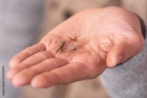 Fisherman showing fishing fly hook in hand palm .