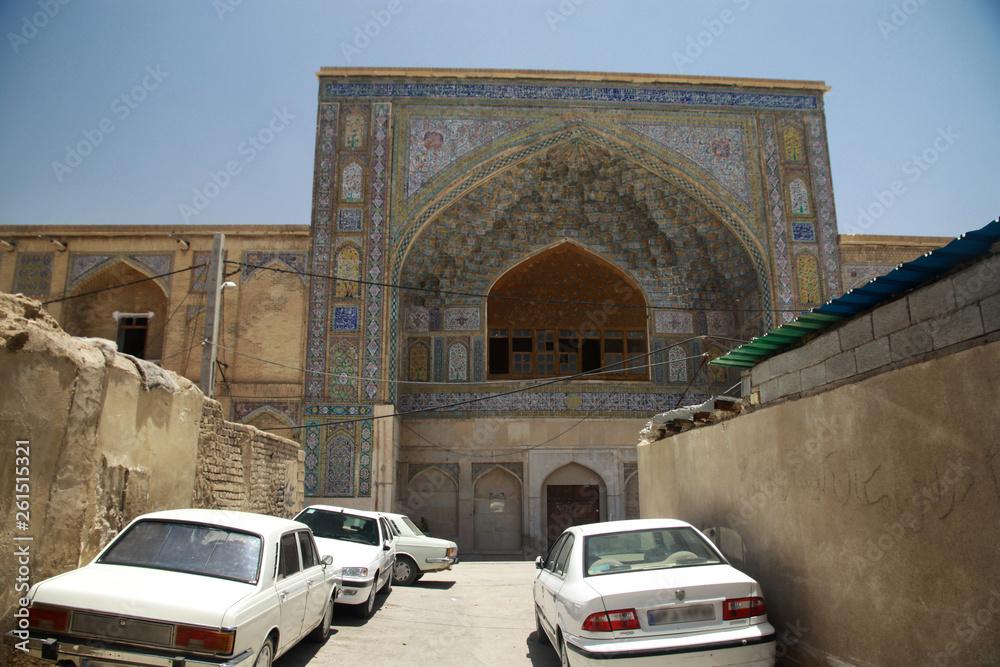 zaniedbany stary i zabytkowy budynek w mieście w iranie z zaparkowanymi przed nim białymi samochodami - obrazy, fototapety, plakaty 