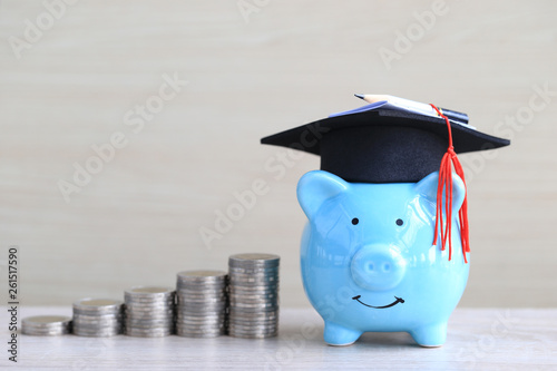 фотографія Graduation hat on blue piggy bank with stack of coins money on wooden background