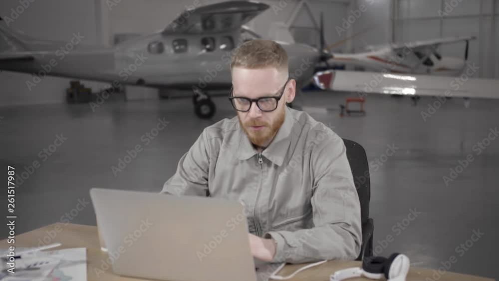 Young pilot sitting at desk in hangar Young pilot sitting at desk in hangar