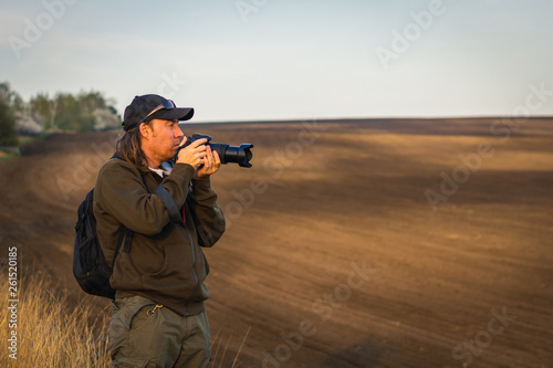 Photographing rural scene during golden hour. Man with camera outdoors