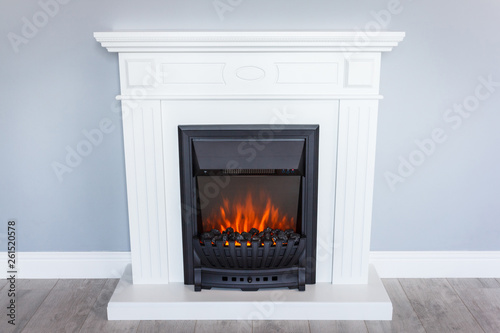 White wooden decorative electric fireplace with a beautiful burning flame. Interior photo on gray background.