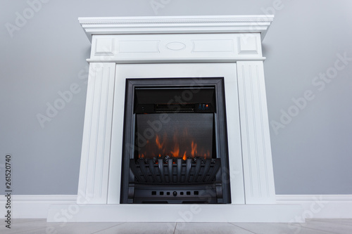 White wooden decorative electric fireplace with a beautiful burning flame. Interior photo on gray background.