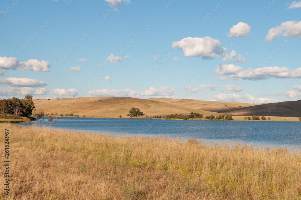 Picturesque landscape of lake and rolling hills with dry yellow grass