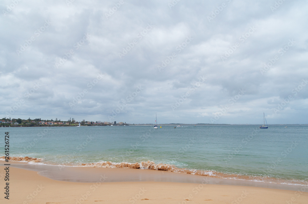 Sandy ocean beach with soft waves and yachts in the lagoon Sandy ocean beach with soft waves and yachts in the lagoon